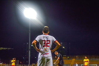 Soccer Player Waiting Under Stadium Lights at Night