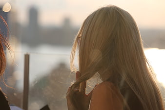 Blonde woman playing with hair on balcony at sunset