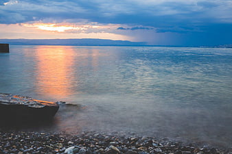 Serene Sunset Over Calm Sea With Pebble Beach