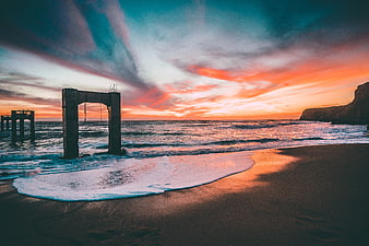 Dramatic Sunset at Abandoned Pier Ruins on Beach