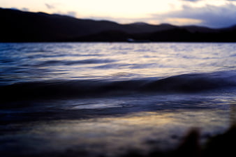 Blurred Ocean Waves at Sunset with Dark Mountain Silhouette
