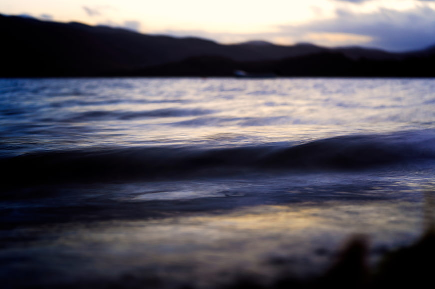 Blurred Ocean Waves at Sunset with Dark Mountain Silhouette