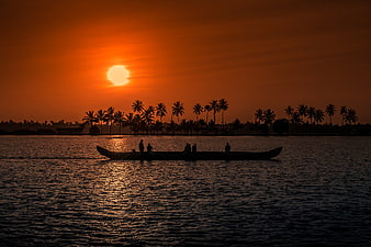 Silhouette of fishermen in boat on backwaters at sunset