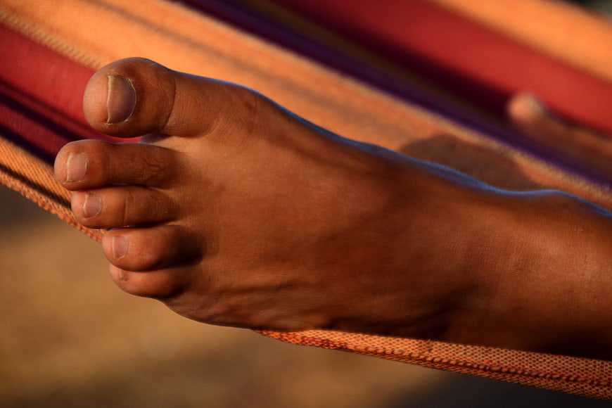 Close-up of bare foot relaxing on colorful striped hammock