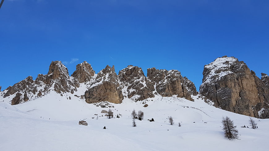 Panoramic view of snow-covered jagged mountain peaks under blue sky