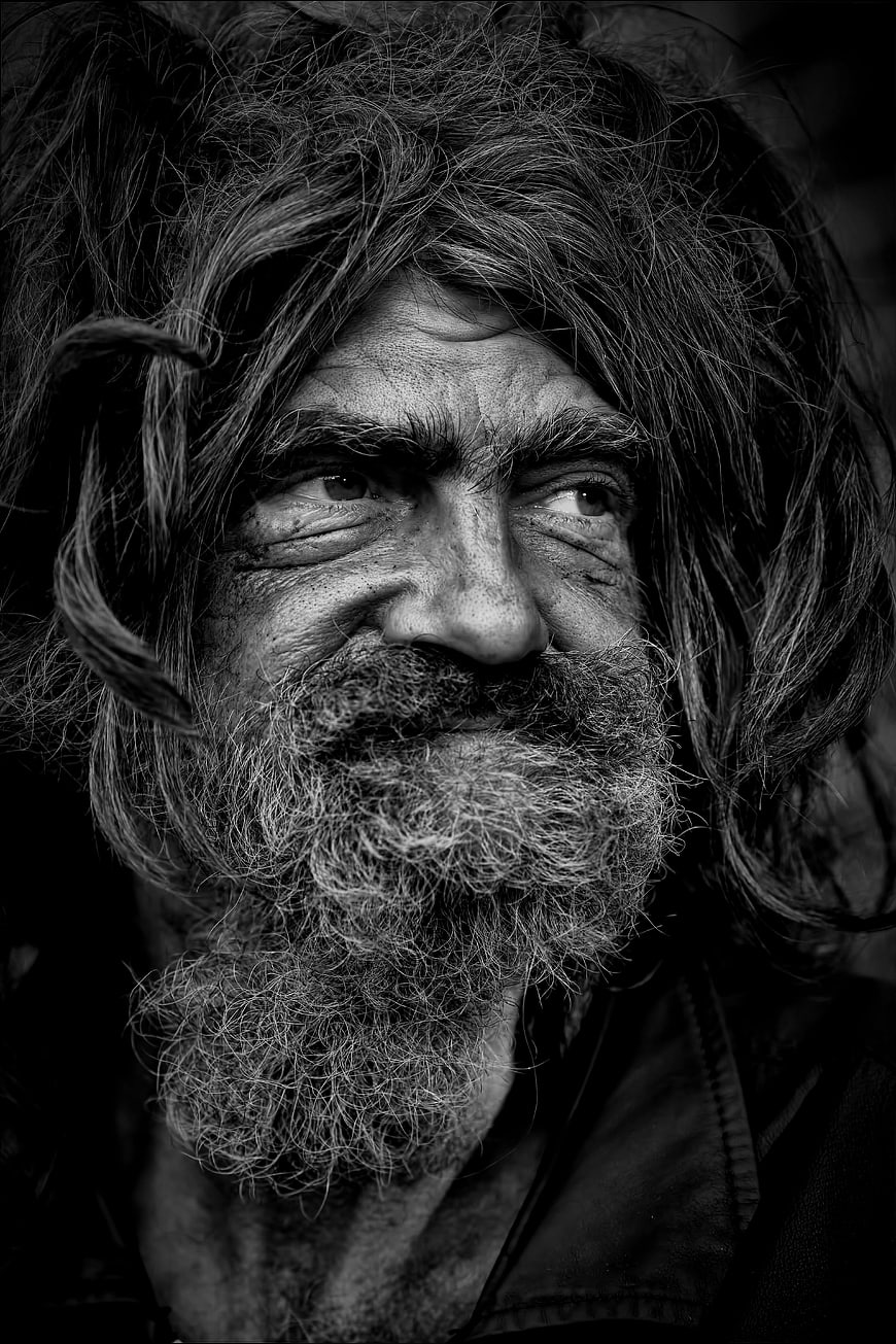 Black and white portrait of elderly homeless man with beard