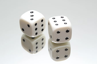 Two white dice on a reflective surface