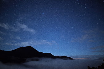 Starry Night Sky Over Mountain Silhouette and Sea of Clouds