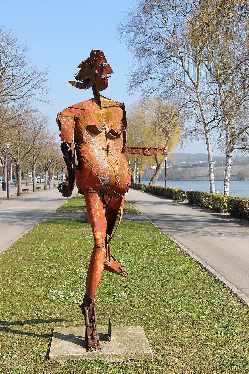 Rusty metal female sculpture in park by lake