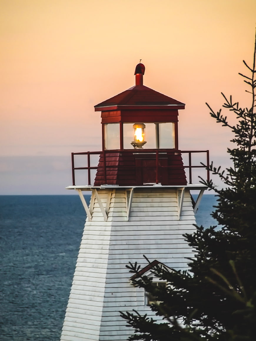 Red and White Lighthouse at Sunset Over Ocean