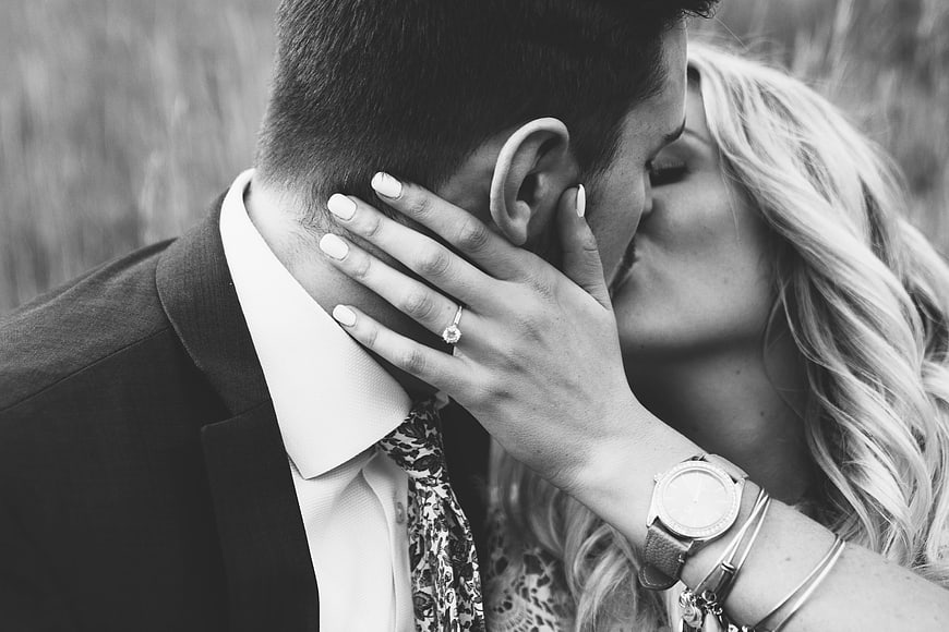 Black and white close-up of couple kissing with engagement ring