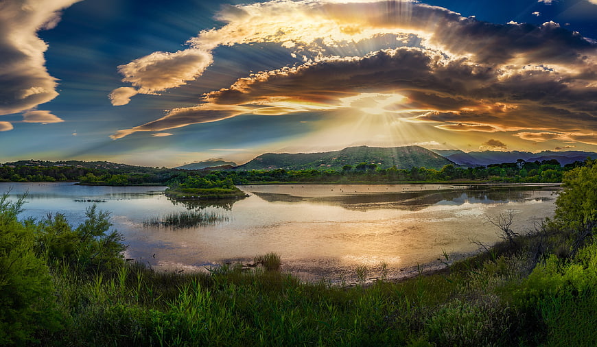 Dramatic Sunrise Over Lake With Sunbeams And Mountain Reflection