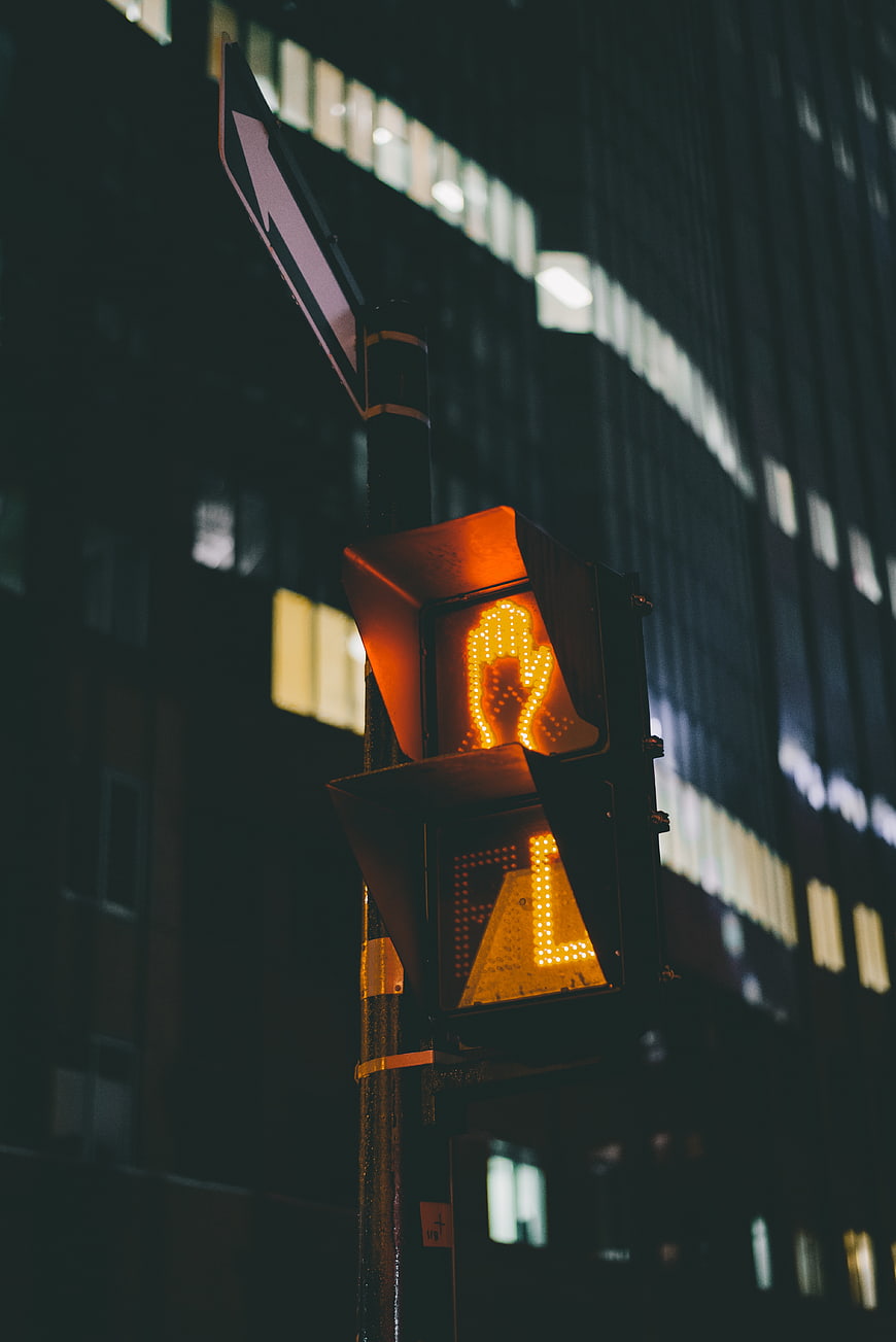 Glowing orange pedestrian traffic light at night in city