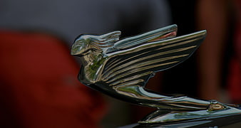 Close-up of a vintage car hood ornament with a blurred background