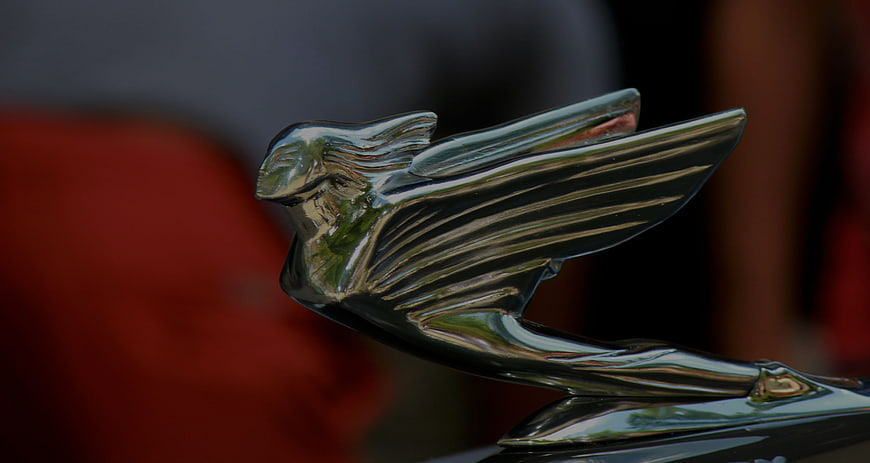 Close-up of a vintage car hood ornament with a blurred background