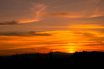 Vibrant orange sunset over silhouetted mountain landscape