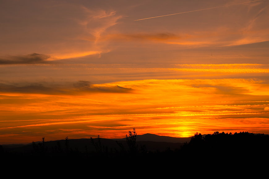 Vibrant orange sunset over silhouetted mountain landscape