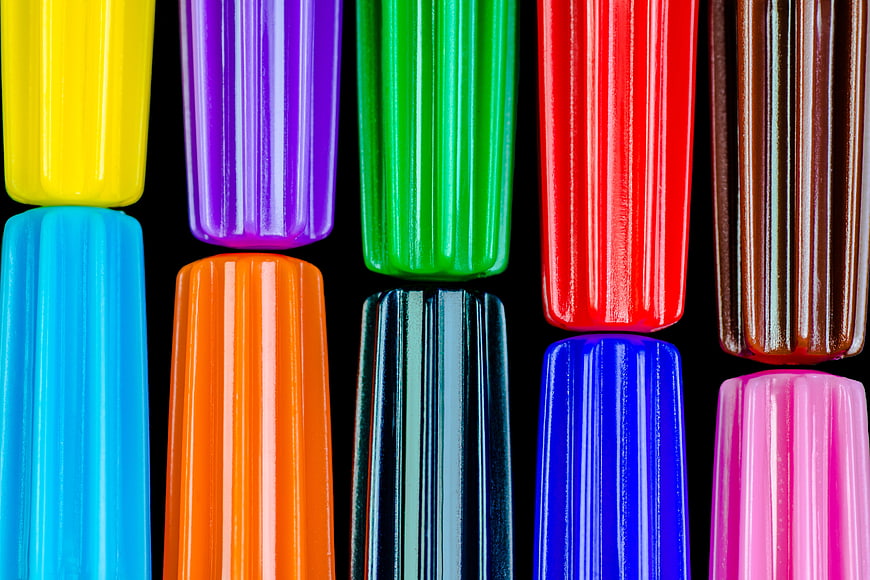 Close-up of colorful ribbed plastic pen caps on black background