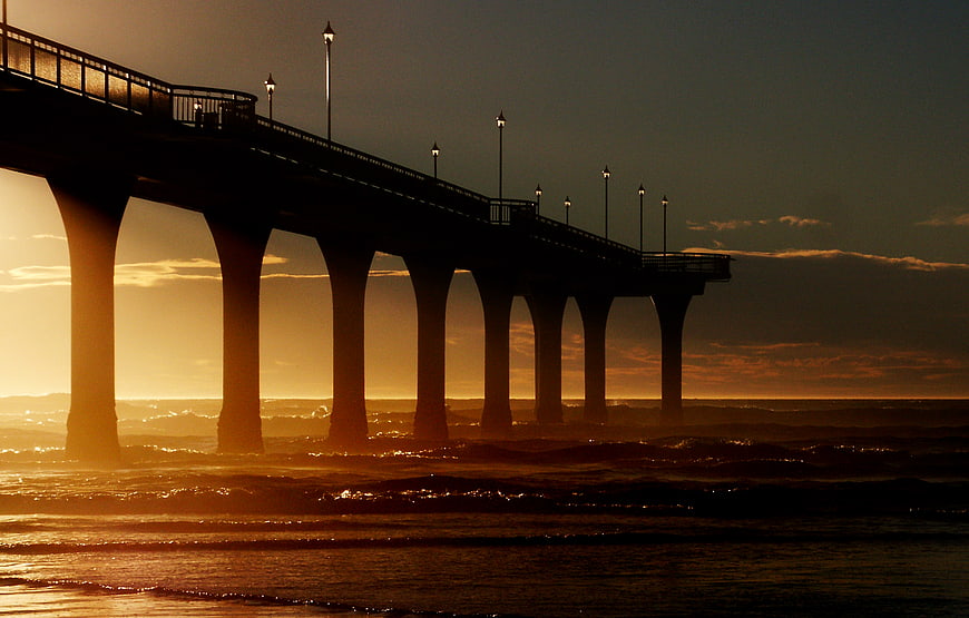Silhouette of pier at sunset over ocean waves