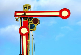 Red and white railroad crossing signal against blue sky