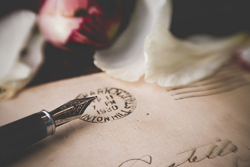 Vintage fountain pen on aged letter with postmark and flowers