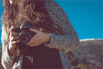 Woman holding Canon DSLR camera outdoors