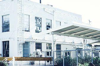 White industrial warehouse building with metal awning and fence