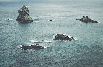 Aerial view of rocky sea stacks in calm blue ocean