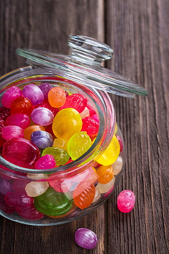 Colorful jelly candies in a glass jar on wooden background