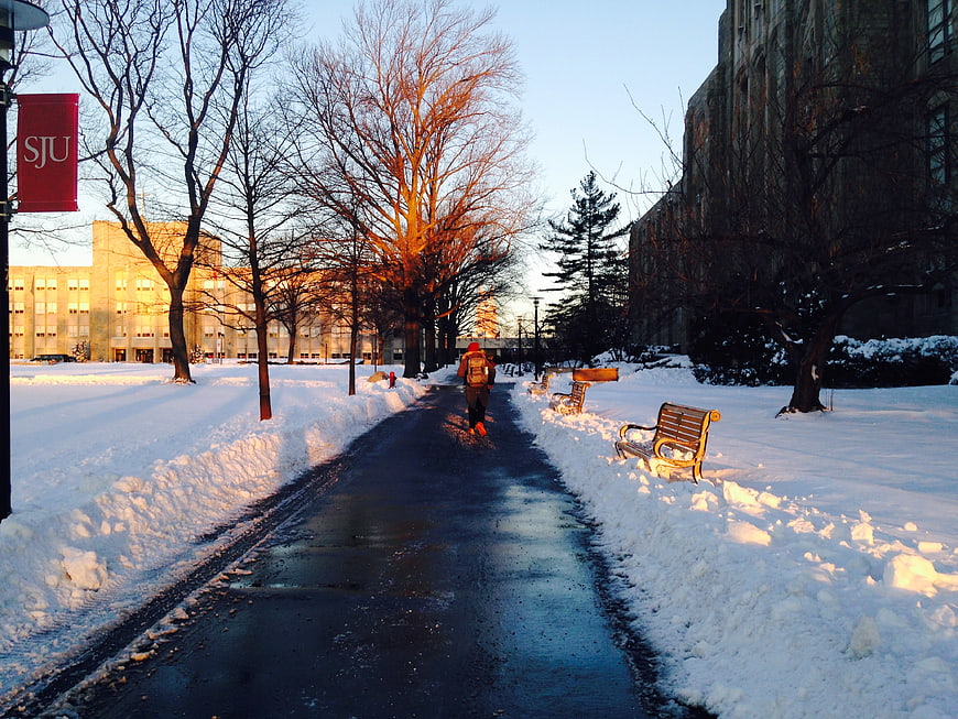 Person walking on snowy path at university campus in winter