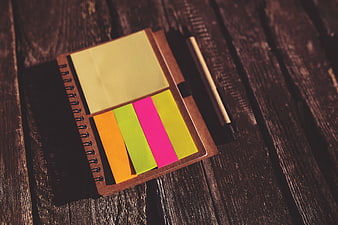 Colorful sticky notes on notebook with pen on wooden table