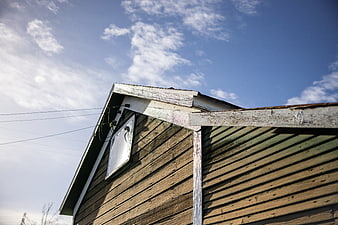 Weathered wooden barn gable against blue sky with clouds