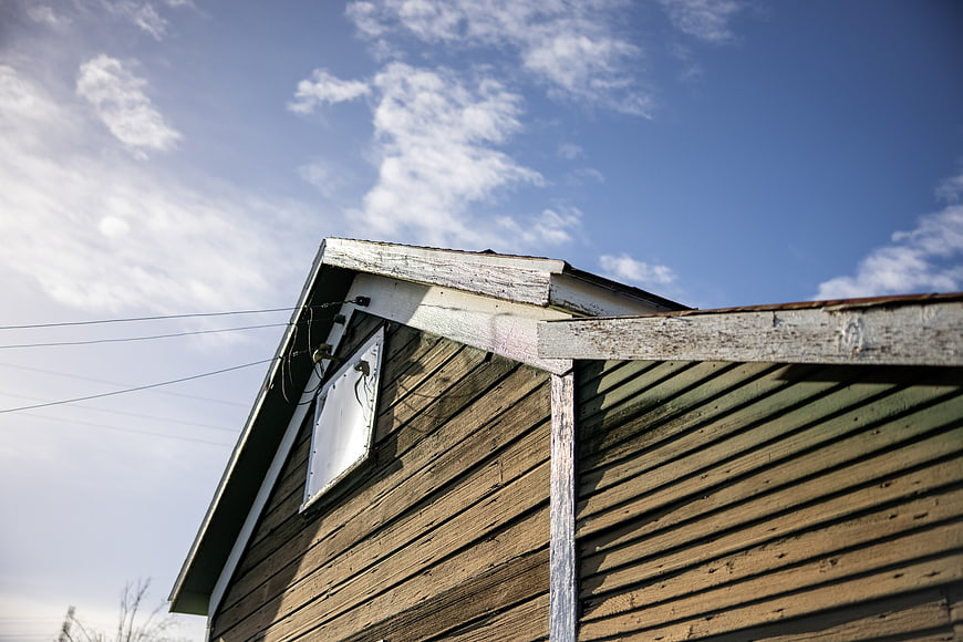 Weathered wooden barn gable against blue sky with clouds