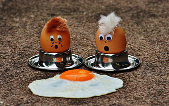 Funny anthropomorphic eggs with googly eyes and hair reacting to fried egg