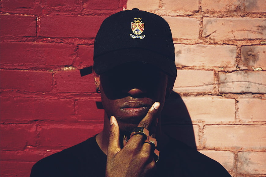 Stylish man in black cap against red brick wall