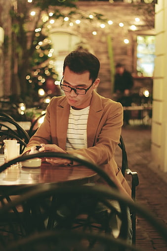Man in Blazer Using Smartphone at Outdoor Cafe at Night