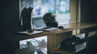 Laptop, helmet, and donut on a cafe counter by window