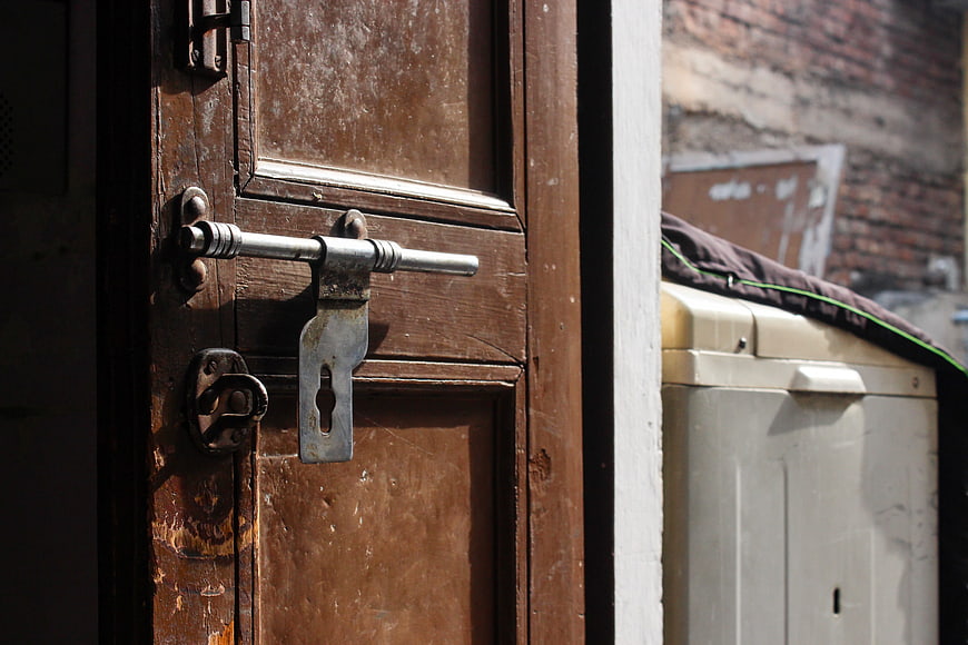 Close-up of vintage wooden door with metal slide bolt latch