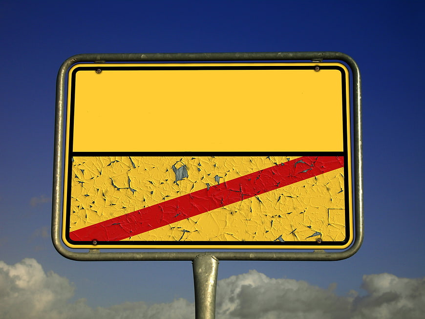 Empty Yellow Road Sign With Red Diagonal Stripe Against Blue Sky