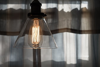Vintage Edison Bulb in Glass Shade with Soft Curtain Background