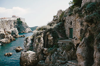 Rugged coastal landscape with stone structure and turquoise sea