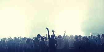 Silhouetted crowd at concert with bright stage lights