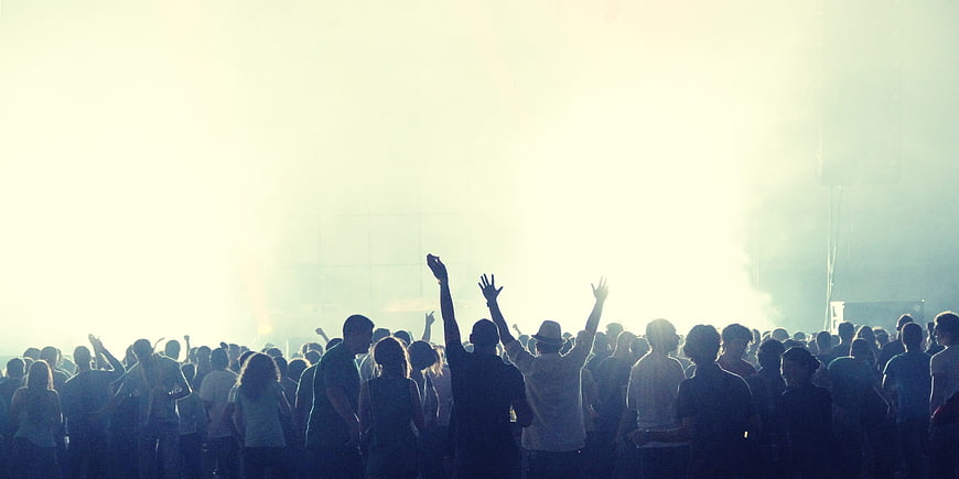 Silhouetted crowd at concert with bright stage lights