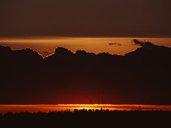 Dramatic Sunset Silhouette with Dark Clouds and Golden Horizon