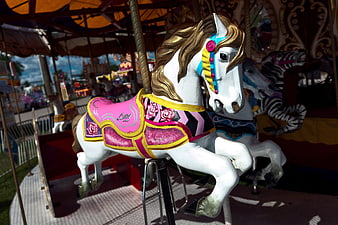 White Carousel Horse with Pink Saddle at Amusement Park