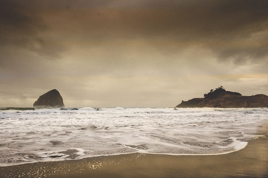Dramatic Stormy Beach with Rocky Outcrop and Crashing Waves