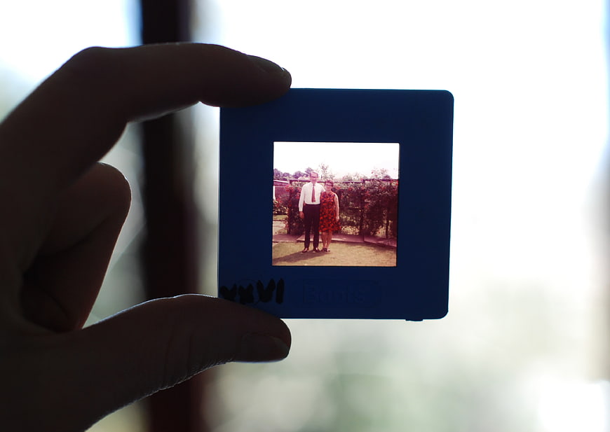 Hand holding vintage film negative of couple in garden