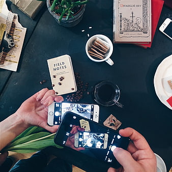 Top view of hands photographing coffee and notebook with smartphones