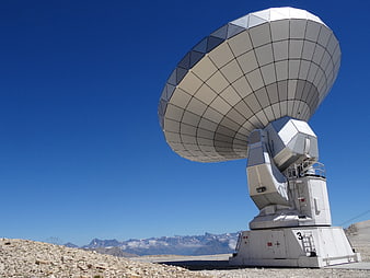 Large White Radio Telescope Antenna Against Blue Sky And Mountains