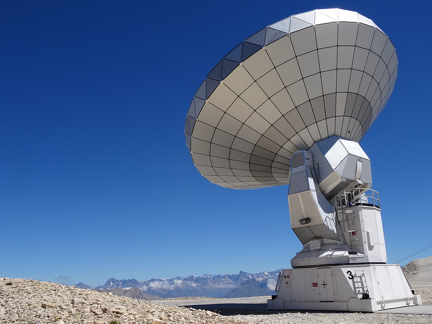 Large White Radio Telescope Antenna Against Blue Sky And Mountains